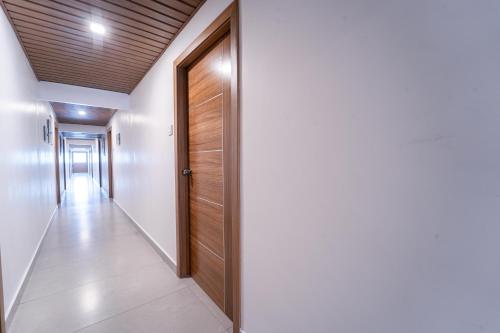 a hallway with a wooden door and white walls at Treebo West Fort Divine - Near Padmanabhaswamy Temple in Trivandrum