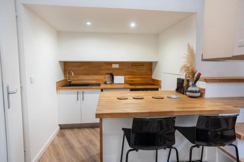 une cuisine avec un comptoir en bois et des chaises noires dans l'établissement Sous les platanes - beau T3 Beaux-Arts, à Montpellier