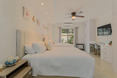 a white bedroom with two beds and a ceiling fan at Cancun Hotel Zone -2 BR Beachfront, Bright and Spacious in Cancún