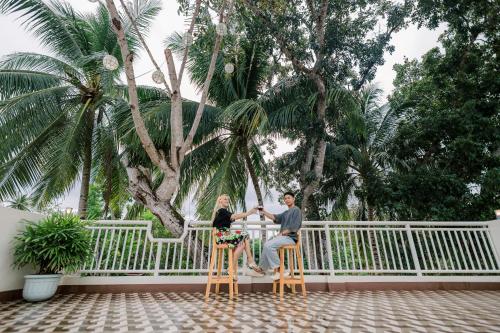 a man and woman sitting on stools in front of a fence at Loboc Riverside Inn & Restaurant in Loboc