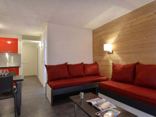 un salon avec un canapé rouge et une table dans l'établissement Appartement rénové chaleureux au cœur de la station, animaux admis - FR-1-181-1951, à La Plagne Tarentaise