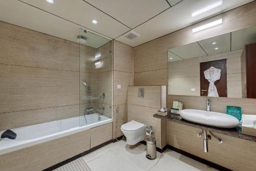 a bathroom with a tub and a toilet and a sink at The Fern Sardar Sarovar Resort Kevadia, Gujarat in Kevadia