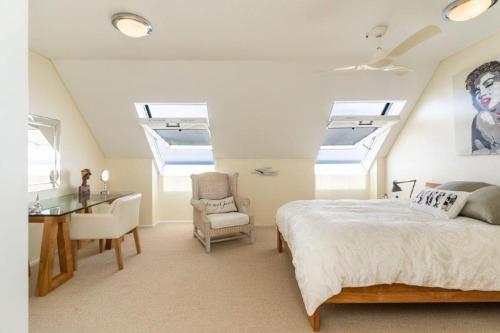a bedroom with skylights and a bed and a desk at Dolphin Beach Penthouse in Cape Town