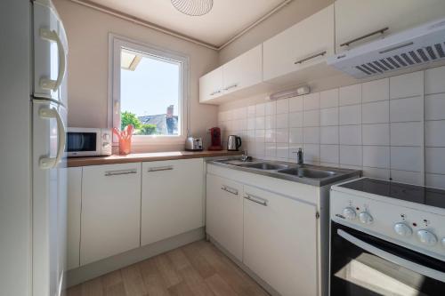 une cuisine avec des armoires blanches, un évier et une fenêtre dans l'établissement Le Filage - Balcon - Wifi, à Laval