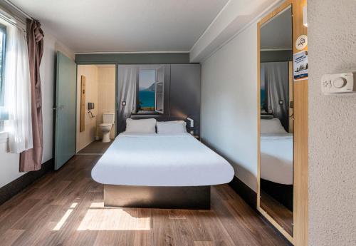 a bedroom with a large white bed and a window at B&B HOTEL CHAMBERY La Cassine in Chambéry