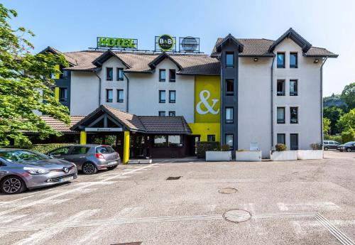 a large building with cars parked in a parking lot at B&B HOTEL CHAMBERY La Cassine in Chambéry