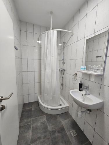 a white bathroom with a shower and a sink at Filipovic rent a car & apartments in Selnica Šćitarjevska