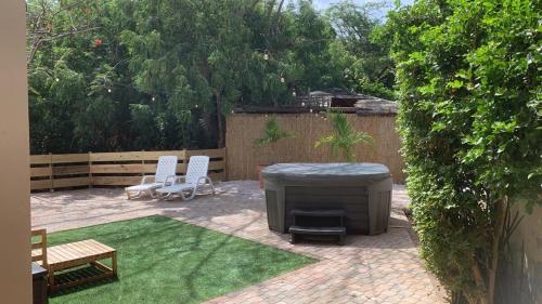 a backyard with a fire pit and two white chairs at One Happy Stay Oranjestad - appartement 2 in Oranjestad