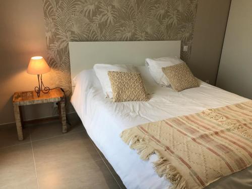 Bett mit weißer Bettwäsche und Kissen neben einem Tisch in der Unterkunft PDM Appartement Paese di Mare in Santa-Lucia-di-Moriani