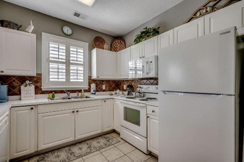 a kitchen with white cabinets and a white refrigerator at Sandy Tee Resort Suite w Giant Pool Oasis in Myrtle Beach