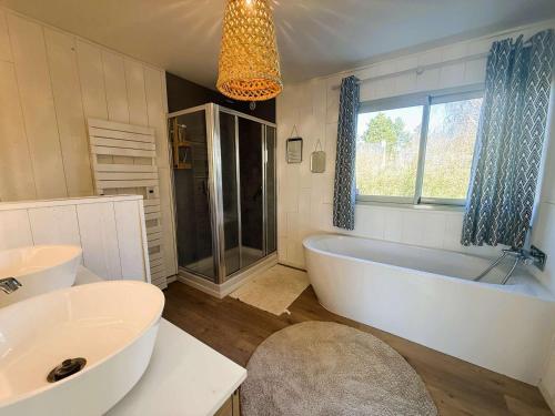 La salle de bains est pourvue d'une baignoire, de 2 lavabos et d'une fenêtre. dans l'établissement Superbe maison rénovée, 250m de l'océan, 12 pers, terrasse, jardin, proche plage Kerleven et golf - FR-1-481-164, à La Forêt-Fouesnant