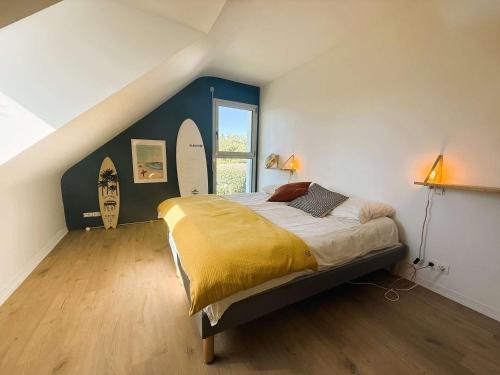 - une chambre avec un lit et une fenêtre avec des planches de surf sur le mur dans l'établissement Superbe maison rénovée, 250m de l'océan, 12 pers, terrasse, jardin, proche plage Kerleven et golf - FR-1-481-164, à La Forêt-Fouesnant