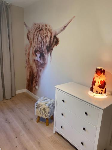 a painting of a cow on a wall next to a dresser at Ferienhaus auffm Hebberg in Attendorn
