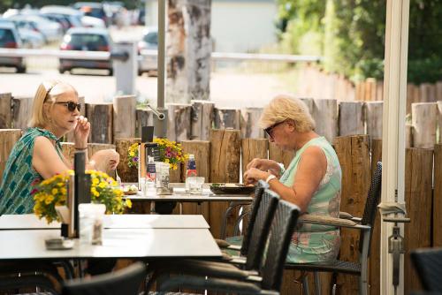 two women sitting at a table at an outdoor restaurant at Strandhotel Duinoord in Vrouwenpolder
