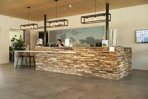 a person sitting at a bar in a restaurant at Strandhotel Duinoord in Vrouwenpolder