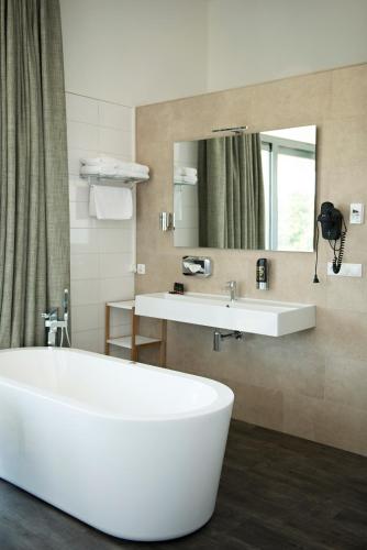 a bathroom with a white tub and a sink at Strandhotel Duinoord in Vrouwenpolder