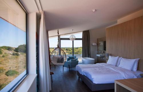 a hotel room with a bed and a large window at Strandhotel Duinoord in Vrouwenpolder