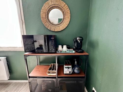 une étagère avec un miroir sur un mur vert dans l'établissement Studio Le république 2, à Dijon