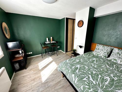 - une chambre dotée d'un mur vert avec un lit et une table dans l'établissement Studio Le république 2, à Dijon