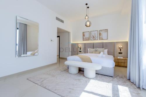 a white bedroom with a white bed and a bench at Sea and Mountain Views 6BR and Assistant's Room Villa, with Heated Pool & BBQ Area, Al Dana, Sharm, Fujairah by Deluxe Holiday Homes in Fujairah
