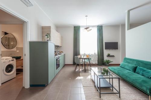 a living room with a green couch and a kitchen at Bazzi, 49 - Bocconi University in Milan