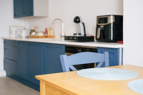 a kitchen with blue cabinets and a table and chairs at Stunning little house, 2 mins from Lyme Regis beach with a sea view to die for. Sleeps 2, free parking, small dog welcome. in Lyme Regis