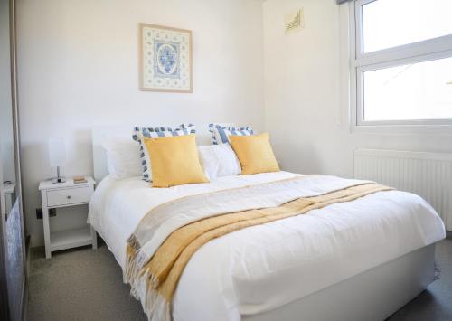 a white bedroom with a large bed with yellow pillows at Stylish 3Bed House with Garden, near Stations, London & Harry Potter studios, great for families and contractors in Watford West Station