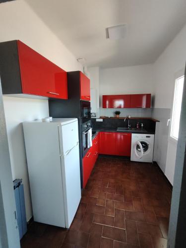 une cuisine avec des armoires rouges et un réfrigérateur blanc dans l'établissement Chez Jean La Provence authentique, à Toulon