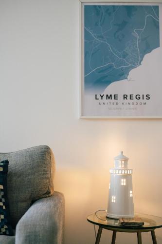 a lamp on a table next to a chair and a lighthouse at Stunning little house, 2 mins from Lyme Regis beach with a sea view to die for. Sleeps 2, free parking, small dog welcome. in Lyme Regis