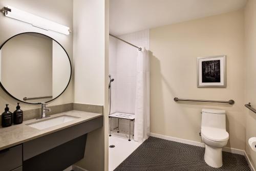 a bathroom with a sink and a toilet and a mirror at The Ann Savannah, Apartments by Marriott Bonvoy in Savannah