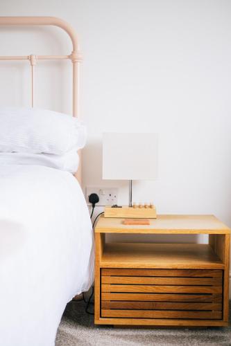 a bed with a nightstand next to a bed with a lamp at Stunning little house, 2 mins from Lyme Regis beach with a sea view to die for. Sleeps 2, free parking, small dog welcome. in Lyme Regis