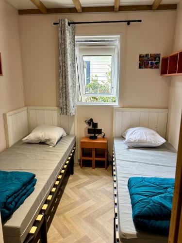 deux lits dans une chambre avec une fenêtre dans l'établissement Le Domaine des Pins, à Saint-Hilaire-de-Riez