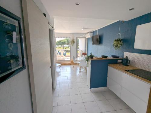Il comprend une cuisine avec des murs bleus et du carrelage blanc. dans l'établissement Sol-y-Days Grand Large, front de mer vue panoramique jardins et mer, au Grau-du-Roi