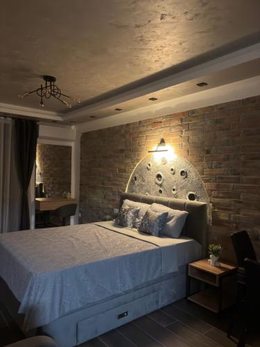 a bedroom with a large bed with a brick wall at "Moon M" Apartman in Vrnjačka Banja