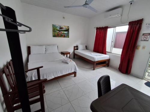 a bedroom with a bed and a chair and a window at Heliconias Hotel in Leticia