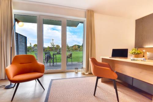 an office with orange chairs and a desk with a laptop at Ferienwohnung Waldkauz 23 im Wreecher Idyll Rügen by ruyastay in Putbus