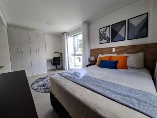 a bedroom with a large bed with orange and blue pillows at Zu Hause, sua casa em Blumenau in Blumenau
