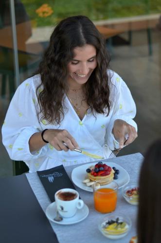 a woman sitting at a table with a plate of food at La Cipressina B&B in Cavaion Veronese