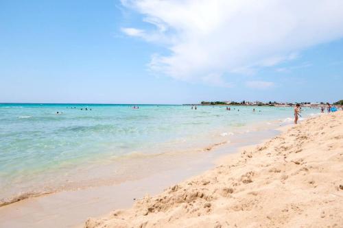 a beach with people swimming in the ocean at Casa Dino con accesso diretto alla Spiaggia di Punta Prosciutto in Punta Prosciutto