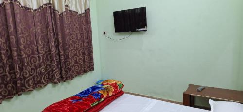 Habitación con sofá y TV en la pared. en Laxmi paying guest house, en Varanasi