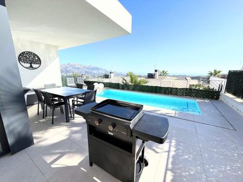 a barbecue on a patio with a table and a pool at Mar y montaña Tu Casa Ideal in Polop