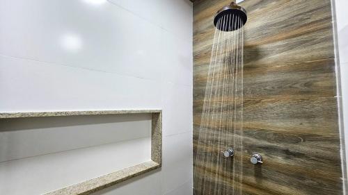 a shower in a bathroom with a wooden wall at Recanto da Susanne in Resende