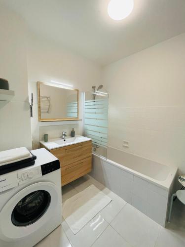 une salle de bain blanche avec une machine à laver à l'intérieur dans l'établissement le Nid des Cèdres, voisin des Thermes et du centre, à Thonon-les-Bains