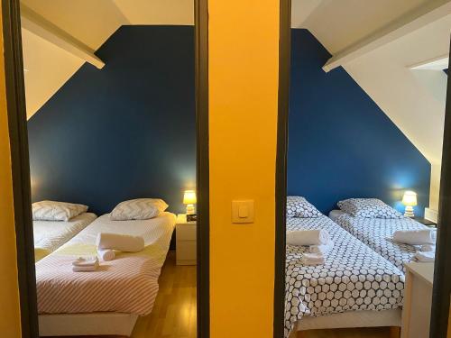 - 2 lits dans une petite chambre aux murs bleus dans l'établissement Cottage au pied des dunes, à Le Touquet-Paris-Plage