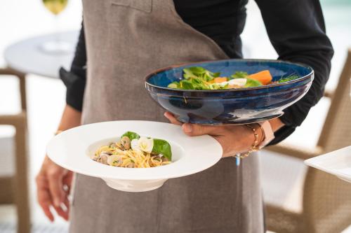 a person holding a bowl of pasta and vegetables at Jesolopalace Hotel & Aparthotel in Lido di Jesolo