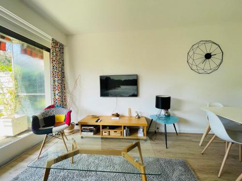 un salon avec une table, des chaises et une télévision dans l'établissement le Nid des Cèdres, voisin des Thermes et du centre, à Thonon-les-Bains