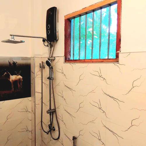 a room with a shower with a microphone on the wall at Dramatic Green Cottage in Udawalawe