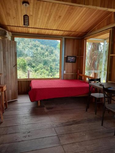 a bedroom with a red bed and a large window at Econative Baru Toucan Cabin con vista al bosque de Platanillo in Platanillo