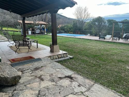 a bench under a gazebo in a yard at Casa de la Senda in Candeleda