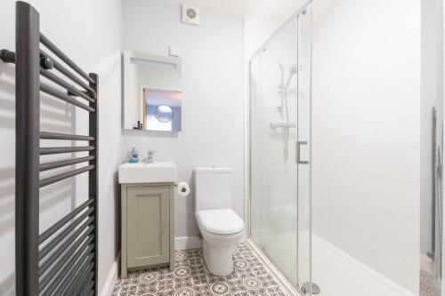 a white bathroom with a toilet and a shower at Castle Mews in Beaumaris